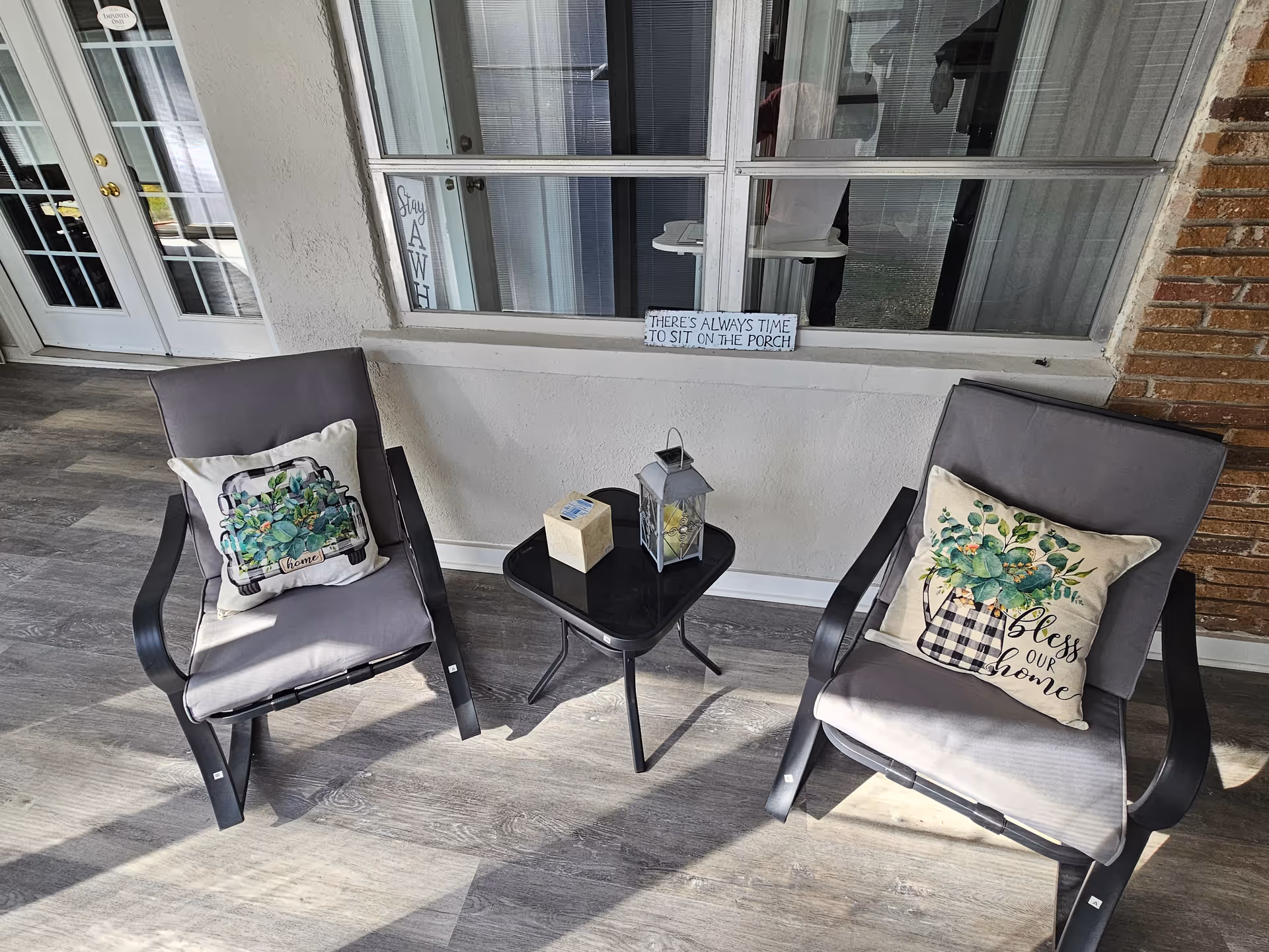 Two cushioned outdoor chairs flank a small table on a covered porch.