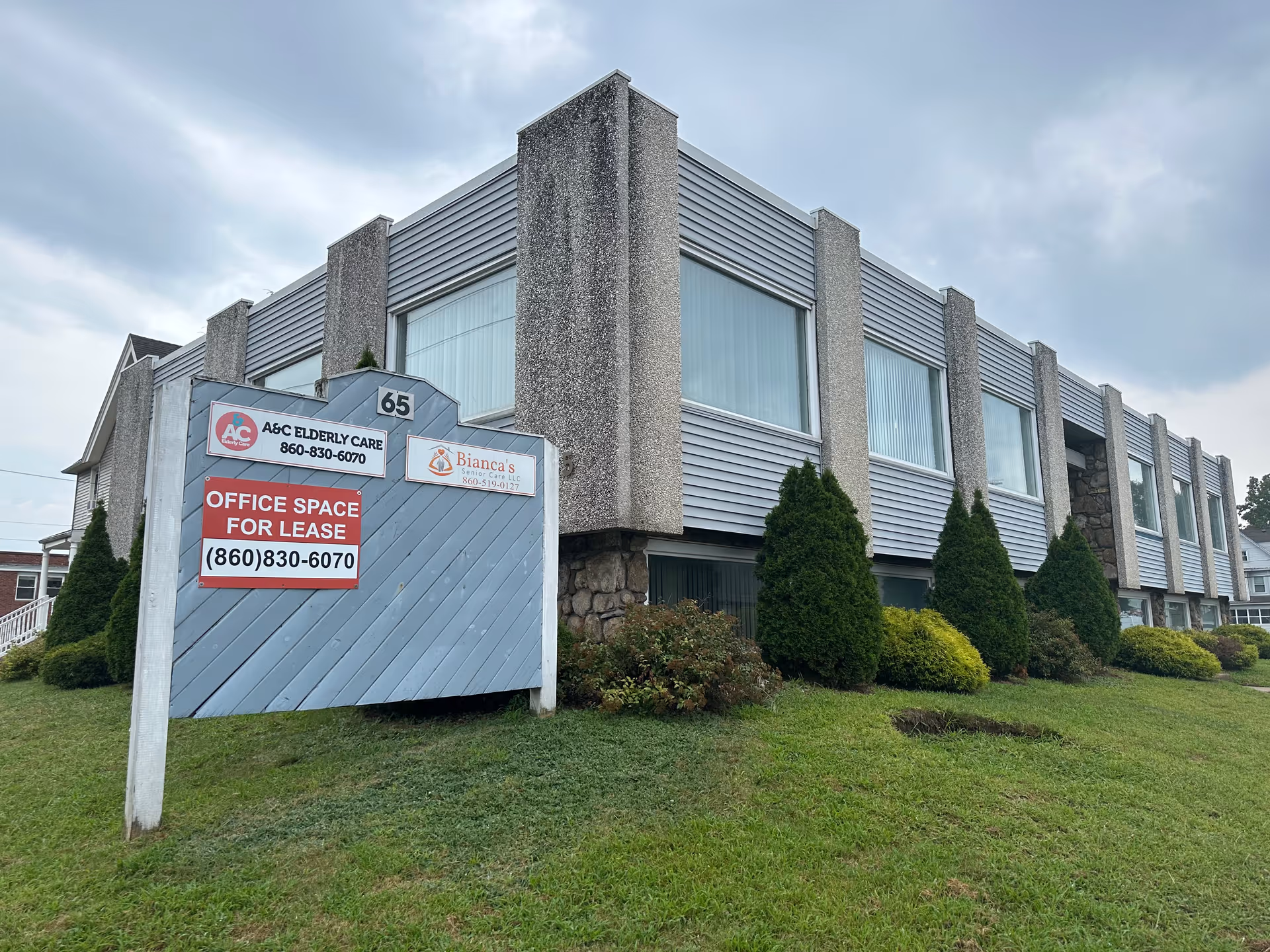 Exterior view of a two-story elderly care facility with signs and shrubs.