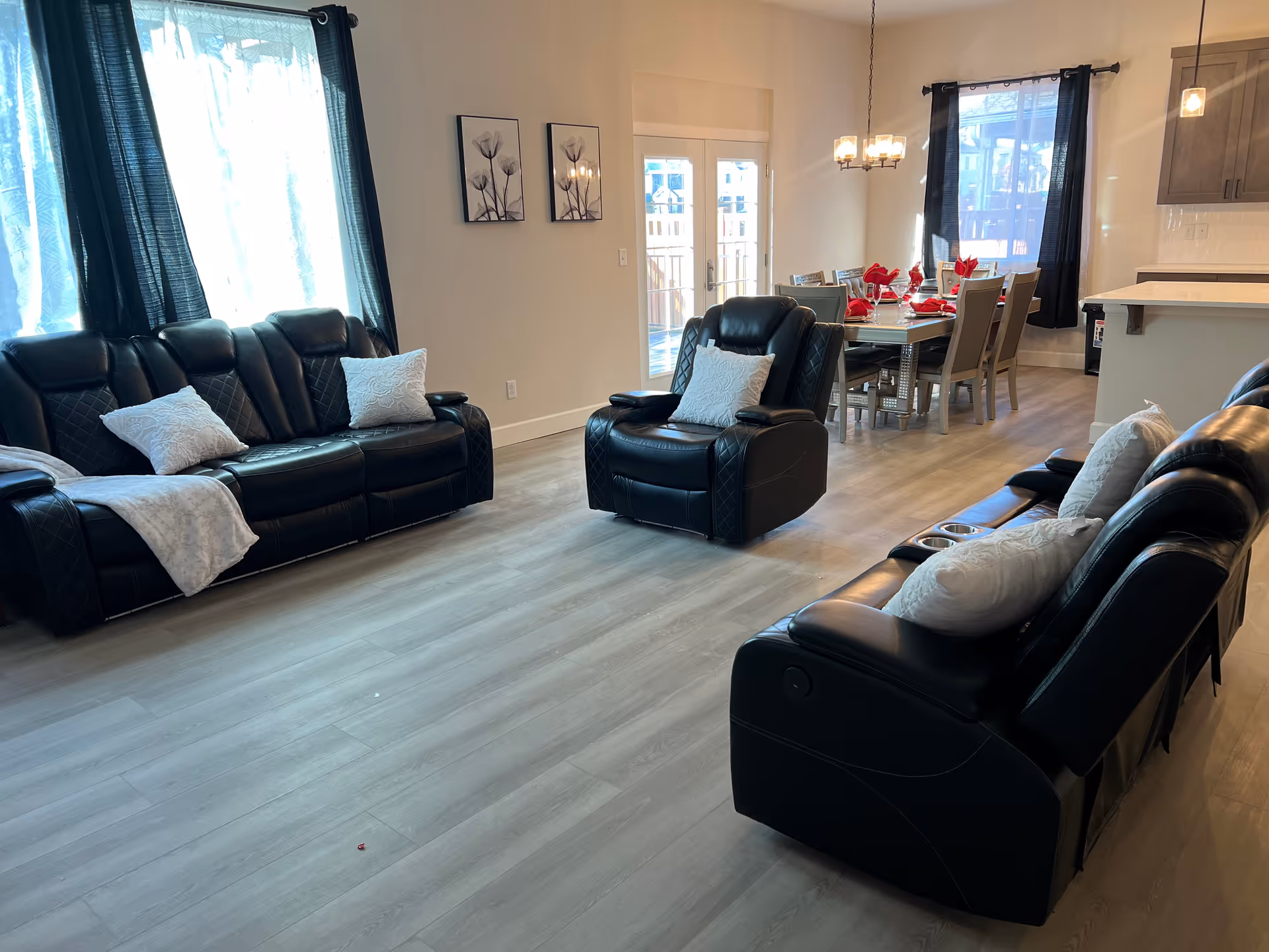 Spacious living room with black leather sofas and dining area in background