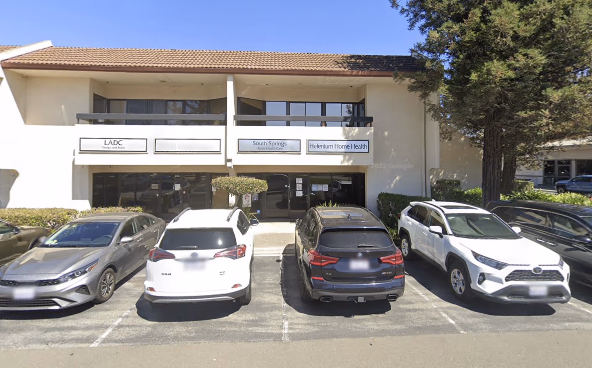 Front view of Helenium Home Health building with a parking lot and signs.