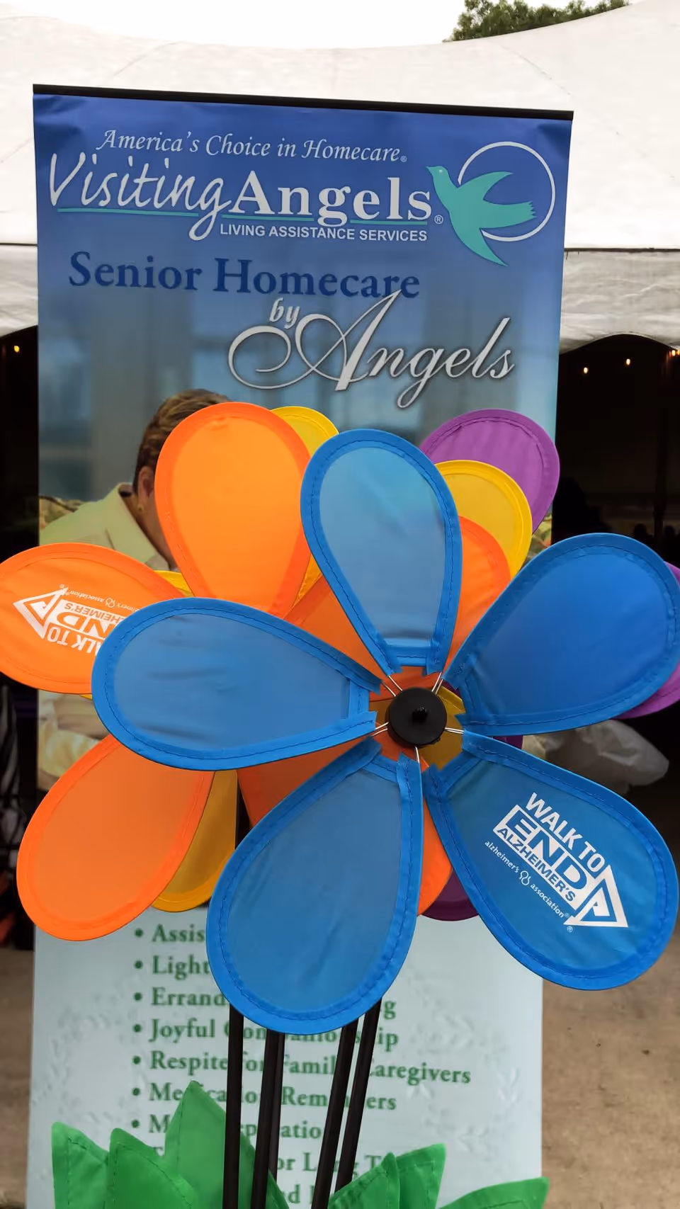 Outdoor banner for Visiting Angels Senior Homecare with a large colorful flower wind spinner.