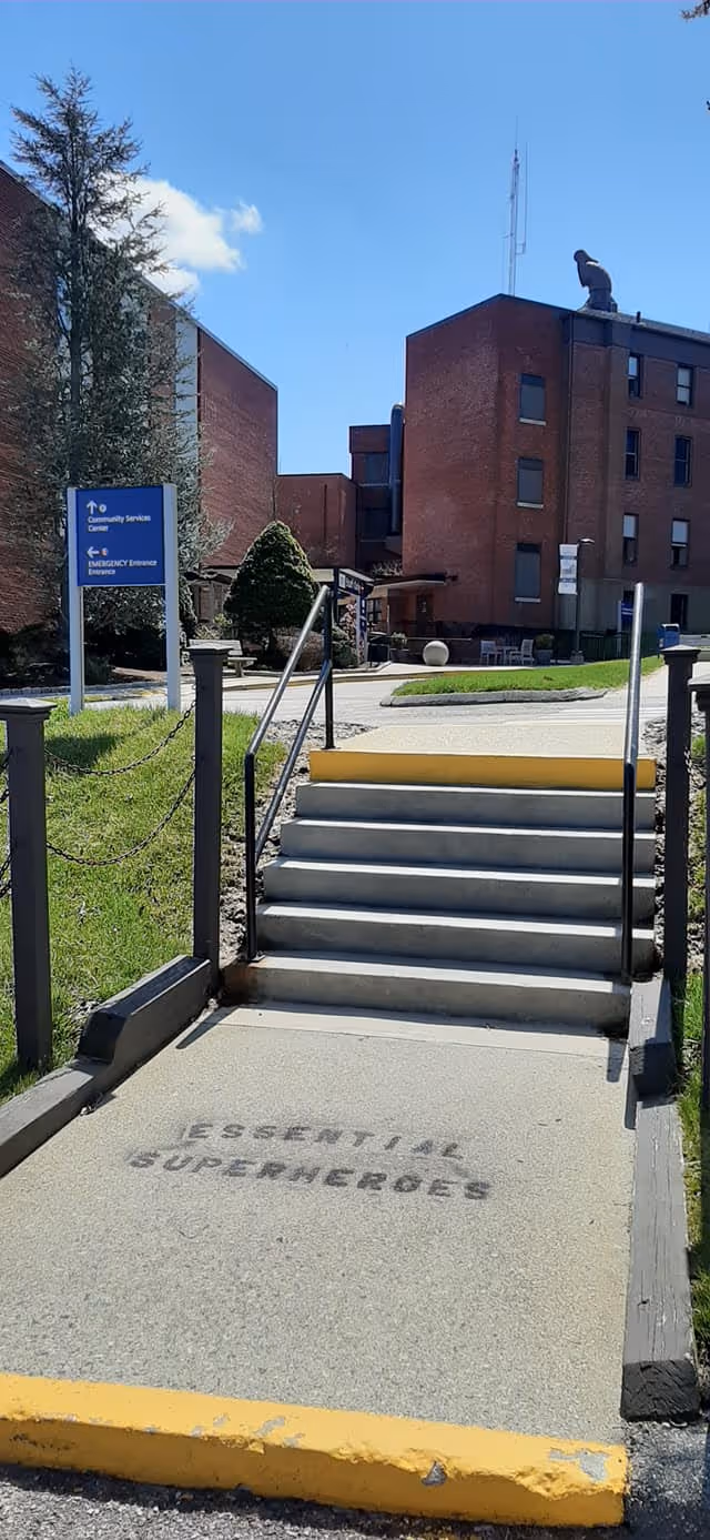 Day Kimball Healthcare exterior: brick building, steps, blue signs, and clear blue sky.