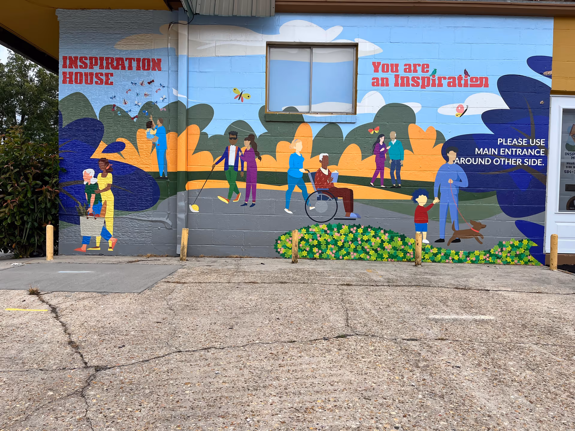 Colorful building exterior mural with people, including a wheelchair user, at Inspiration House.