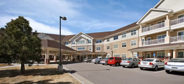 Exterior view of The Courtyards at Mountain View with parked cars and a multi-story building.