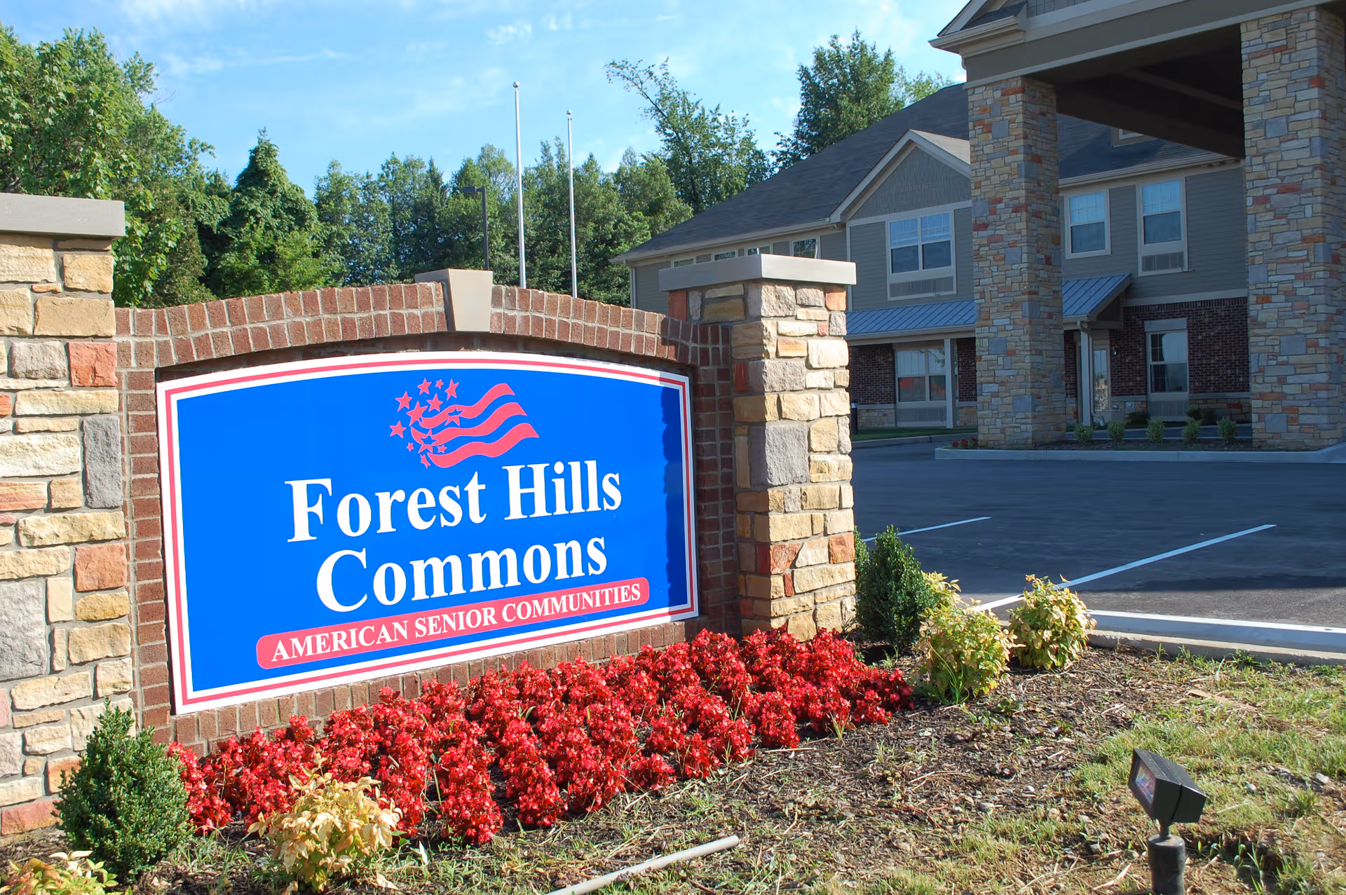 Blue Forest Hills Commons sign framed by brick pillars beside the building entrance.