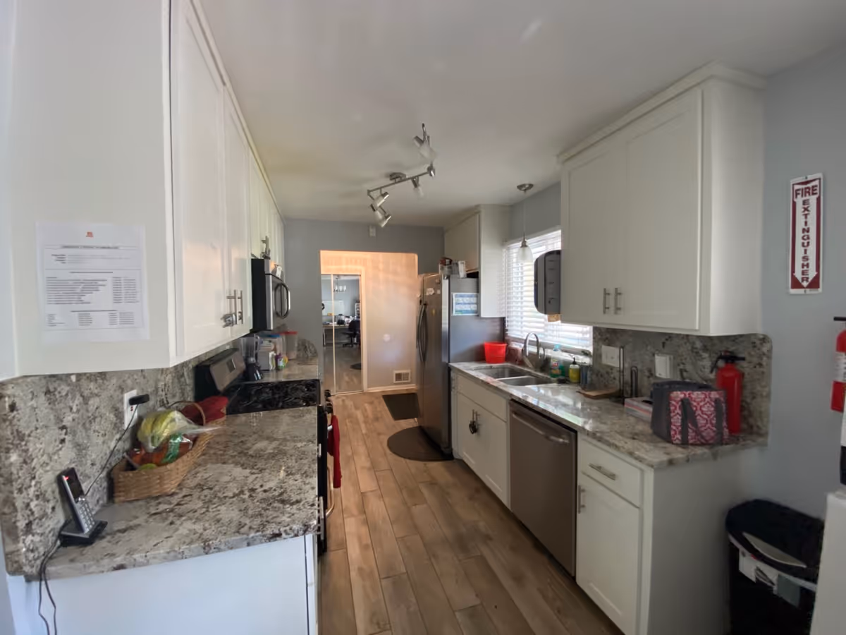 Bright kitchen in a senior living facility with white cabinets and granite countertops.