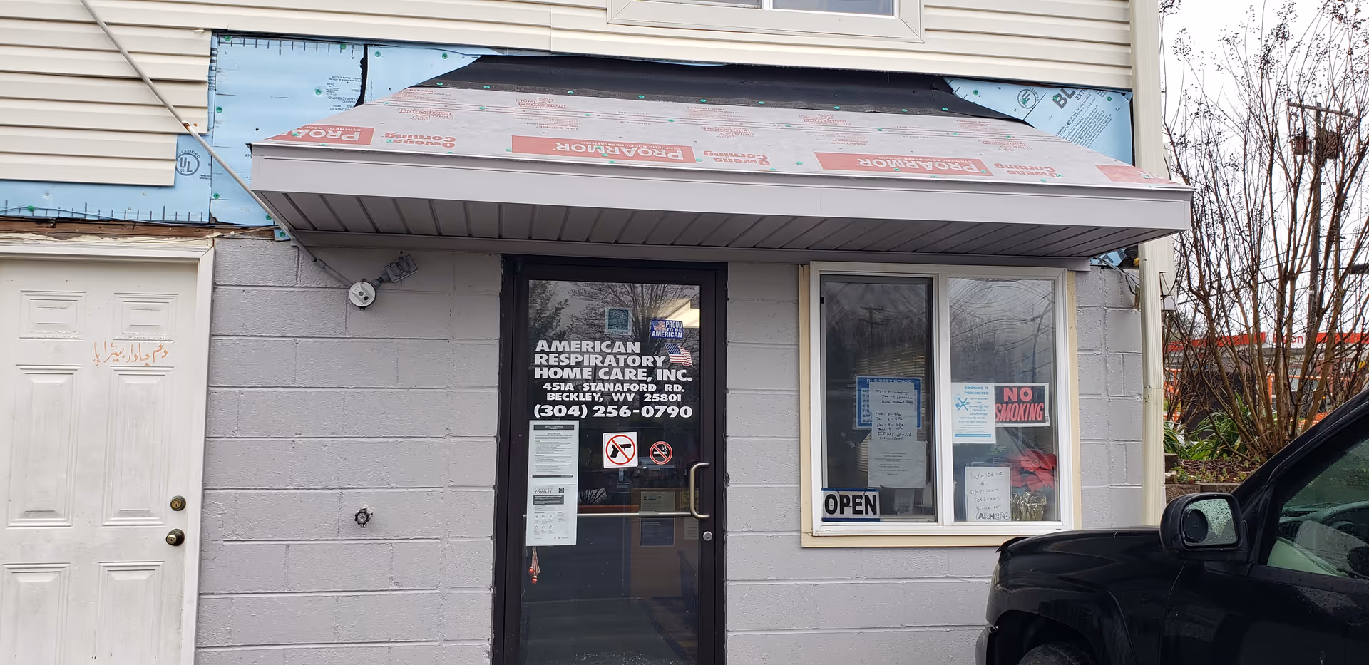 Front entrance of American Respiratory Home Care building with glass door and window signs.