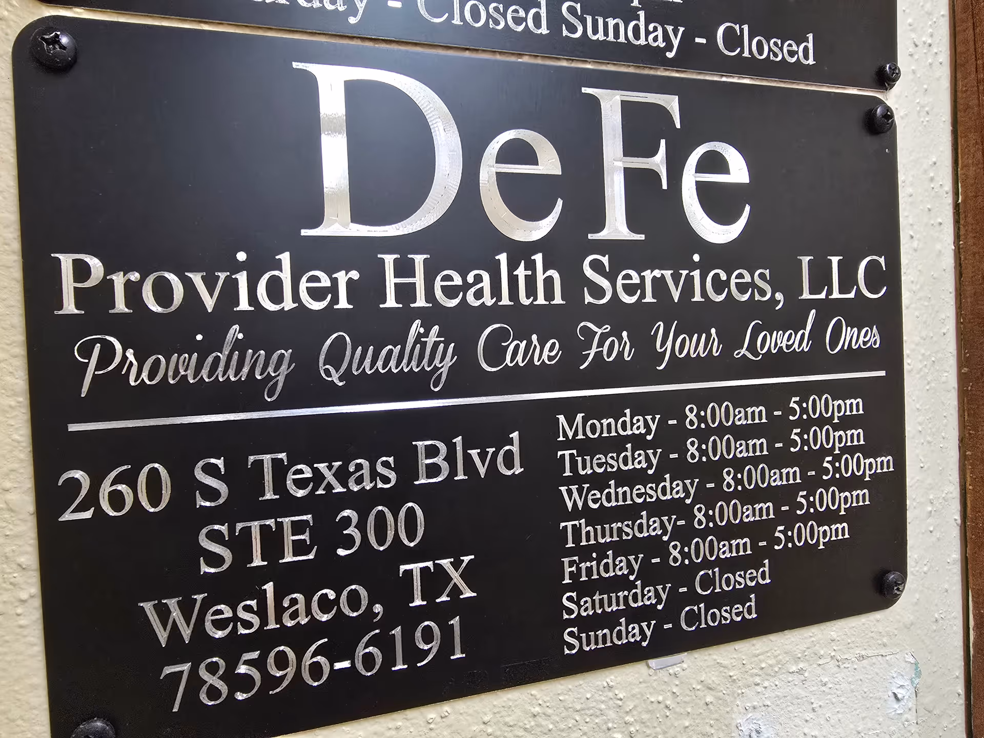 A black sign on a wall displays De Fe Provider Health Services LLC and address information.