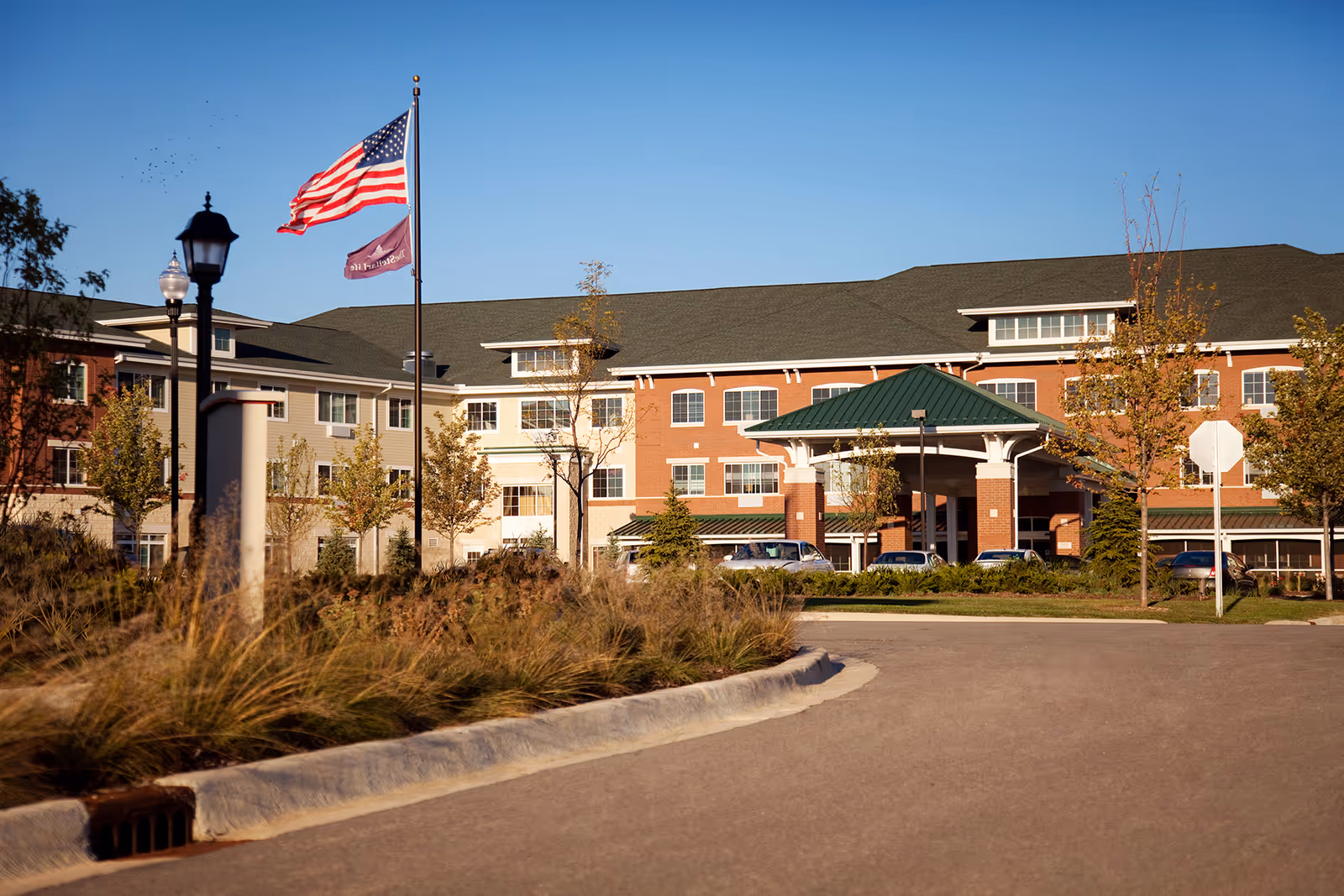 Exterior view of StoryPoint Romeoville facility with flag, entrance canopy, and parked cars.