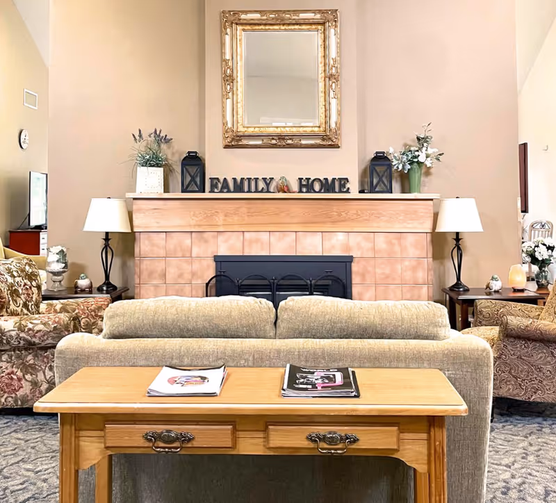 Cozy senior living room with a fireplace, mantel, and seating around a coffee table.