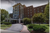 Multi-story brick senior living facility with a landscaped entrance and curved driveway.
