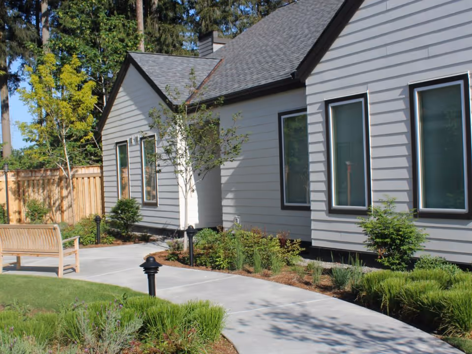 Exterior view of The Cottages of Covington outdoor area with path, bench, and landscaping.