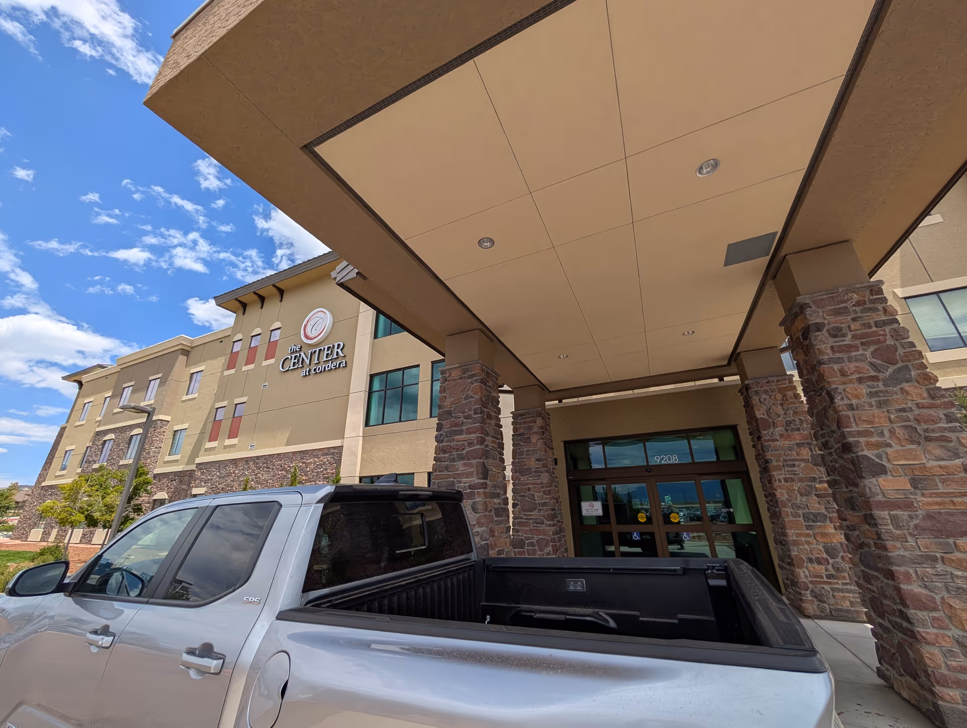 Exterior view of Center at Cordera entrance with stone pillars and a pickup truck.