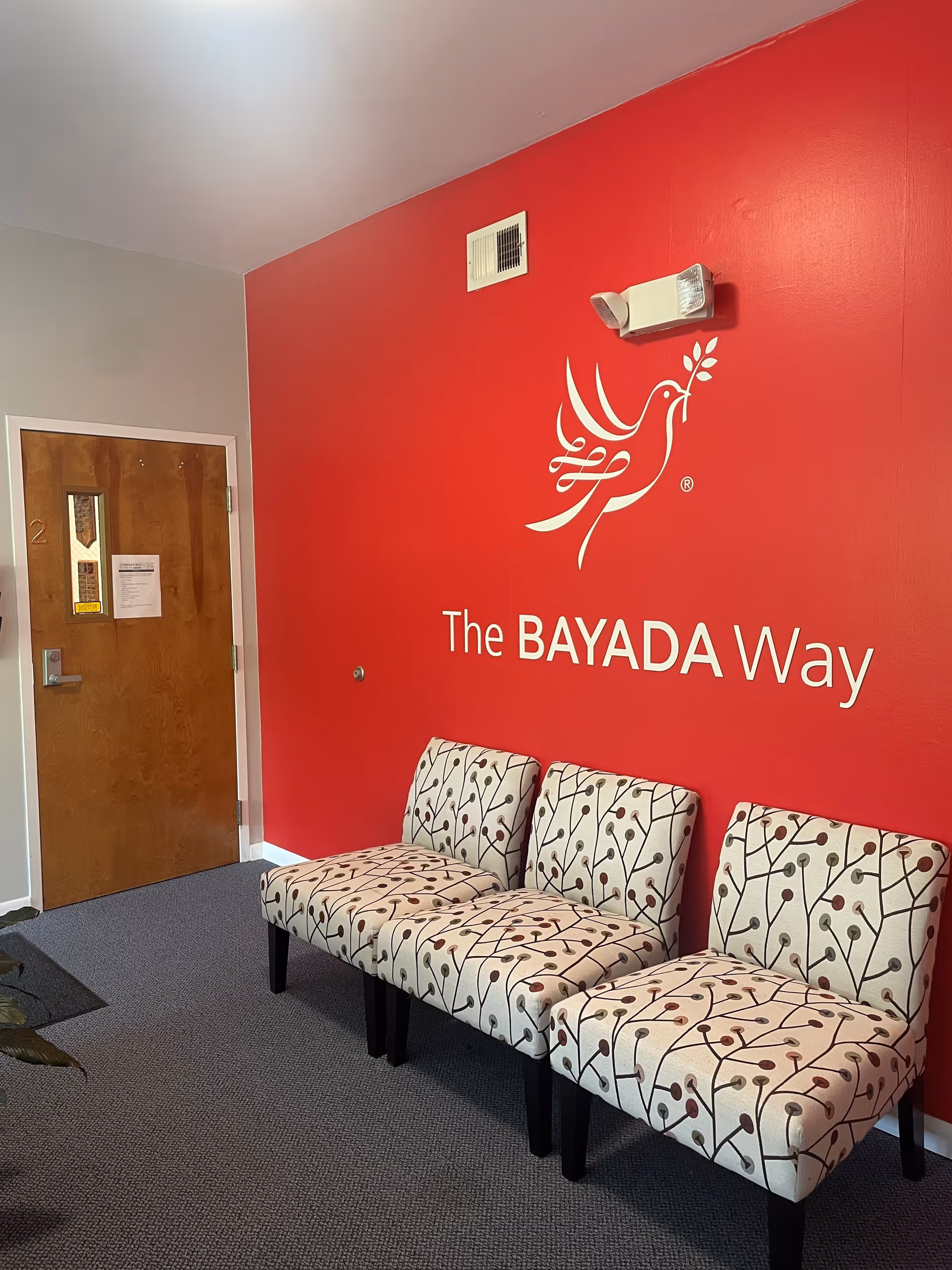 Red-walled interior seating area with patterned chairs and BAYADA branding.