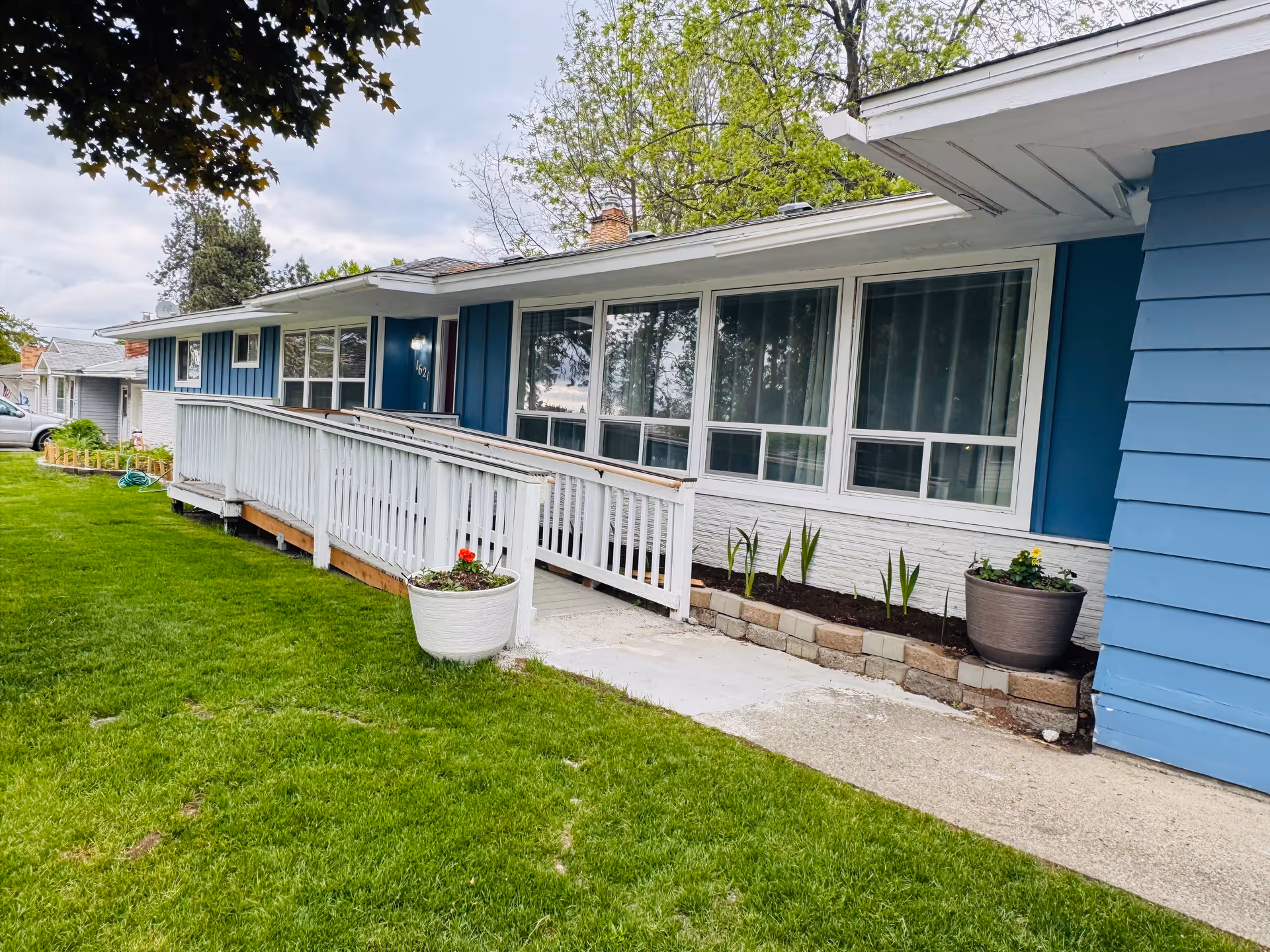 Blue single-story facility exterior with a ramp, large windows, and a green lawn.