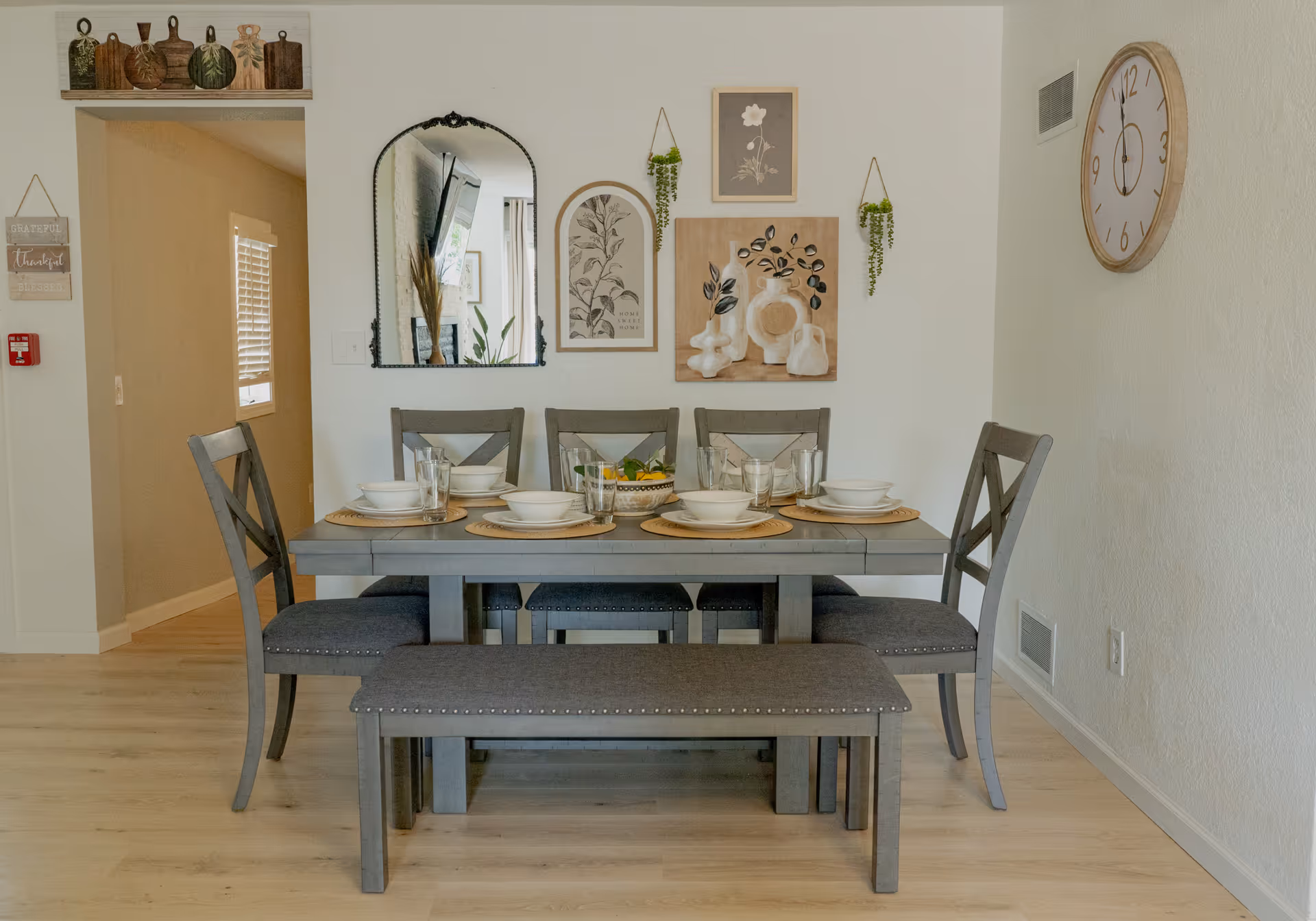 Cozy dining room at Cozy Cottage Senior Living with gray table, chairs, bench, and wall art.