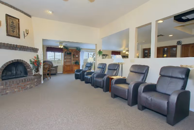 Red Mountain Reflections lounge with row of recliners, fireplace, and warm neutral decor.