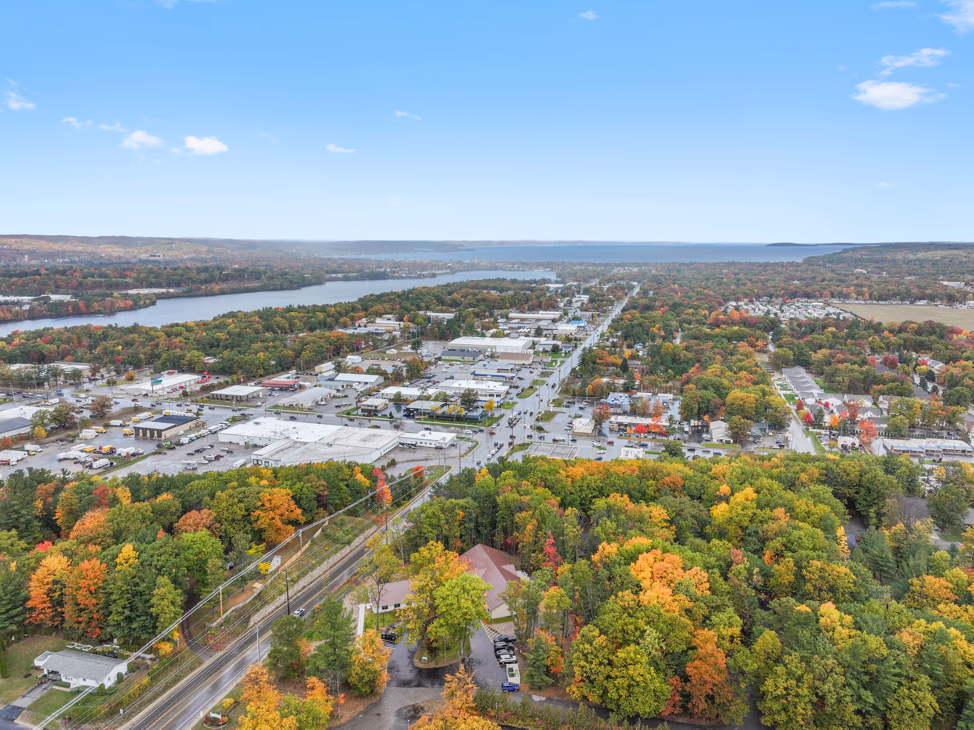 Aerial view of a town with autumn trees, river, and distant shoreline.