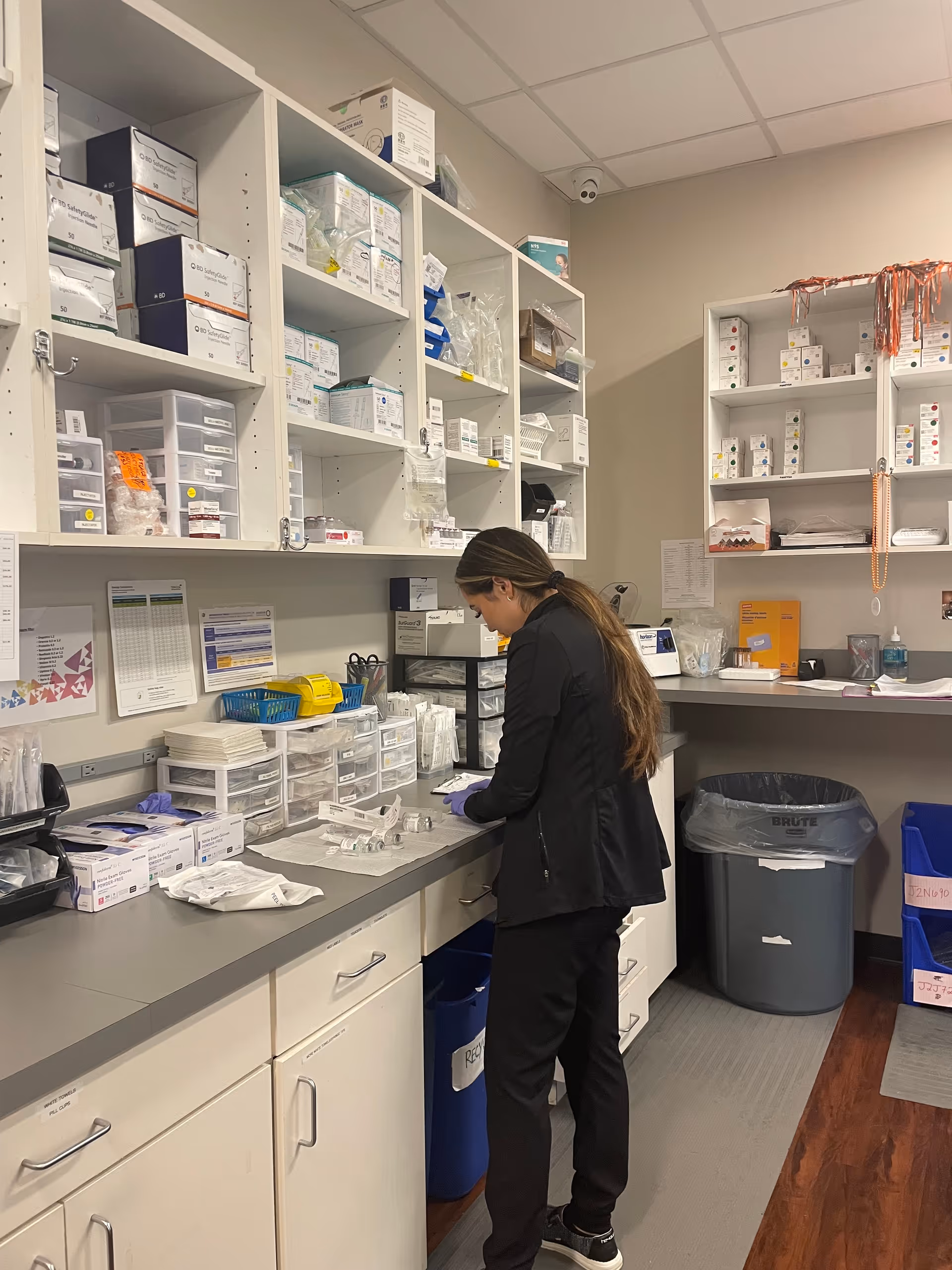 A staff member organizes medical supplies at a cluttered supply counter.