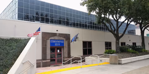 Exterior view of Michael E. DeBakey VA Medical Center entrance with ramp, flag, and trees.