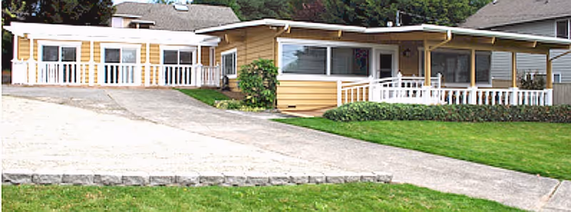 Exterior view of a beige senior living facility with a ramp and a white porch.