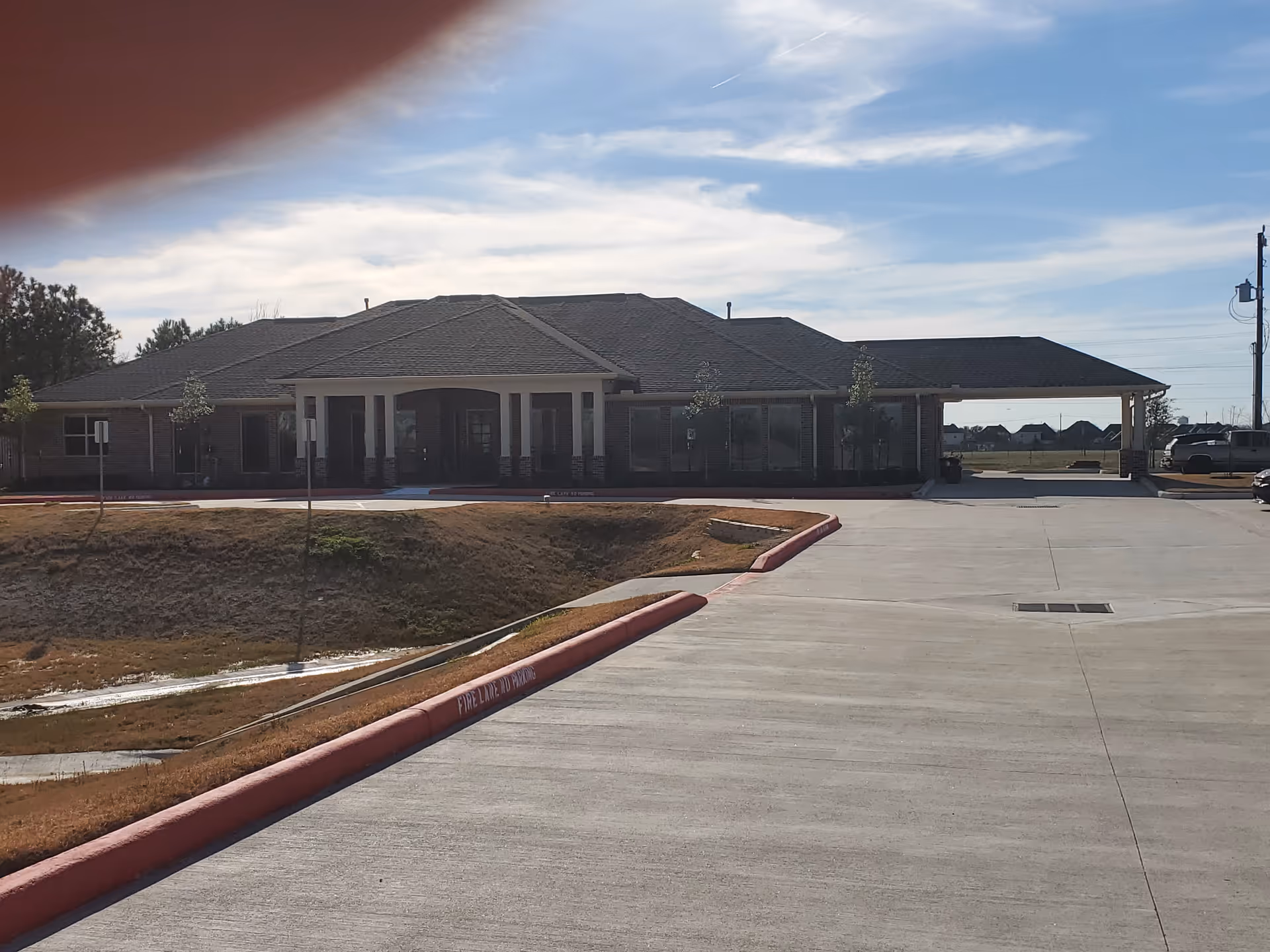 Single story Serenity Gardens Deer Park facility exterior with a wide driveway and entrance.