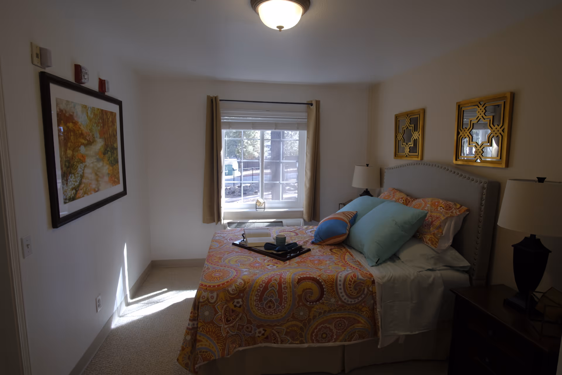 Cozy bedroom with a bed, nightstands, lamps, and a window at Brookdale Flagstaff.