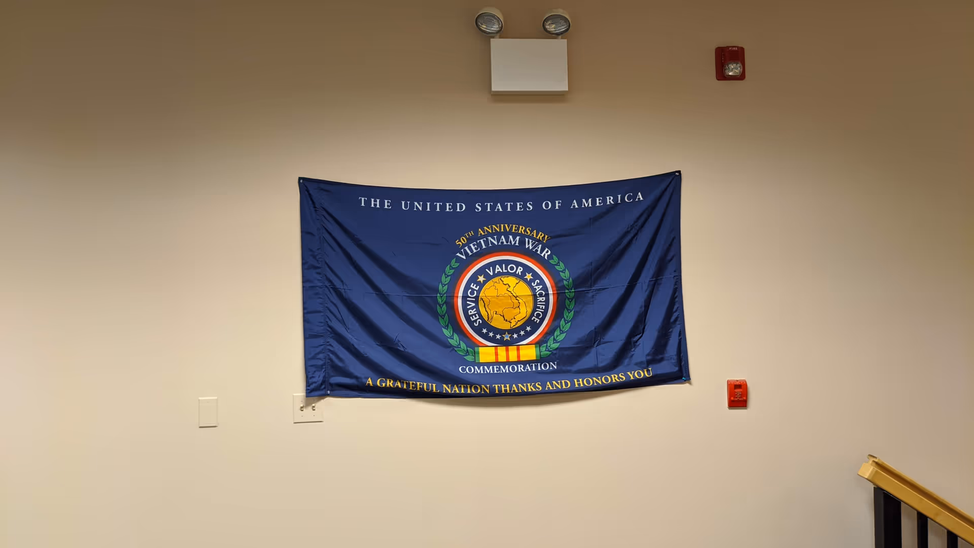 Blue banner commemorating Vietnam War hangs on a beige interior wall.