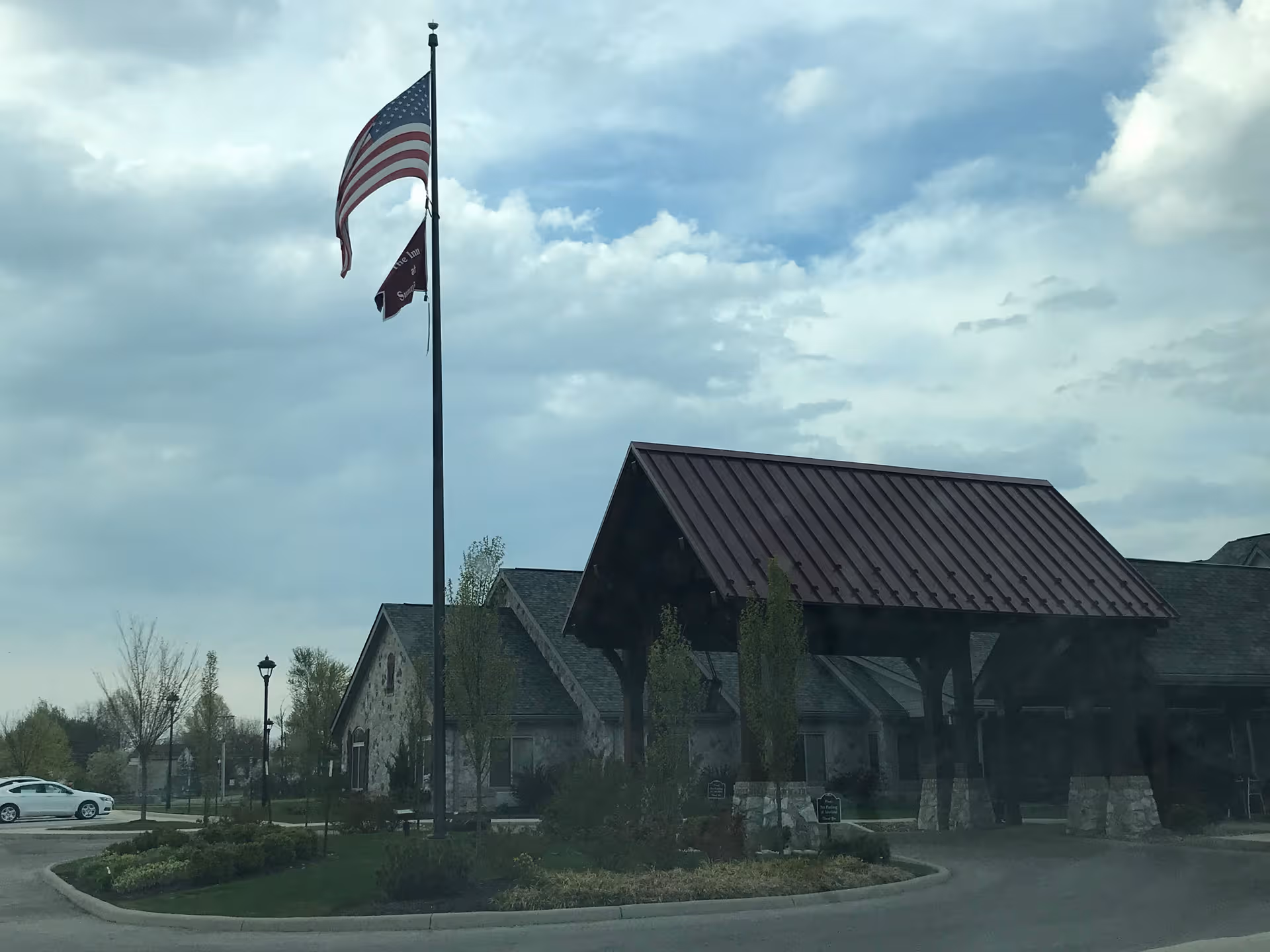 American flag waves beside Inn at Summit Trail entrance under a covered porte-cochere.
