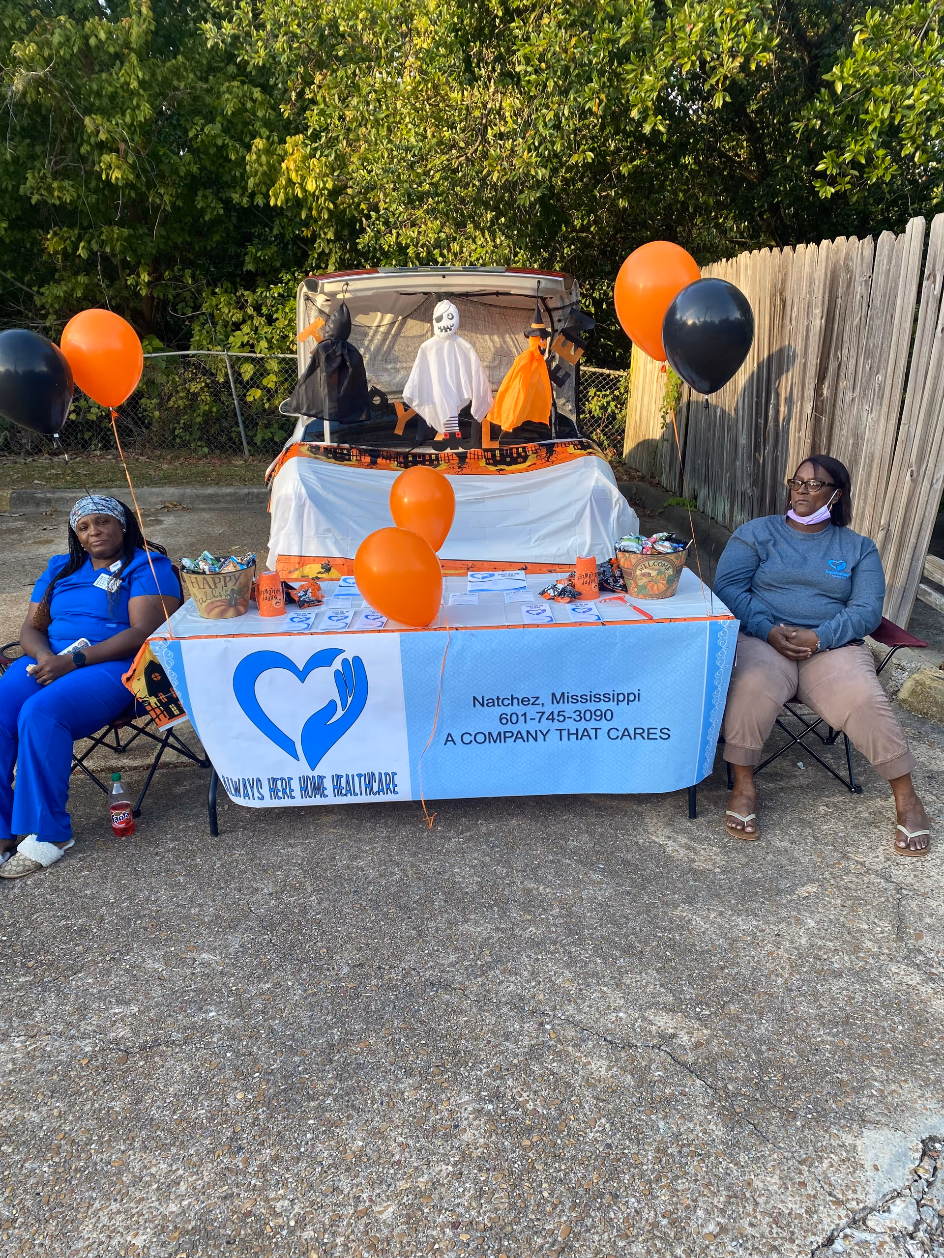Outdoor promotional booth for Always Here Personal Care Services LLC with two caregivers and balloons.