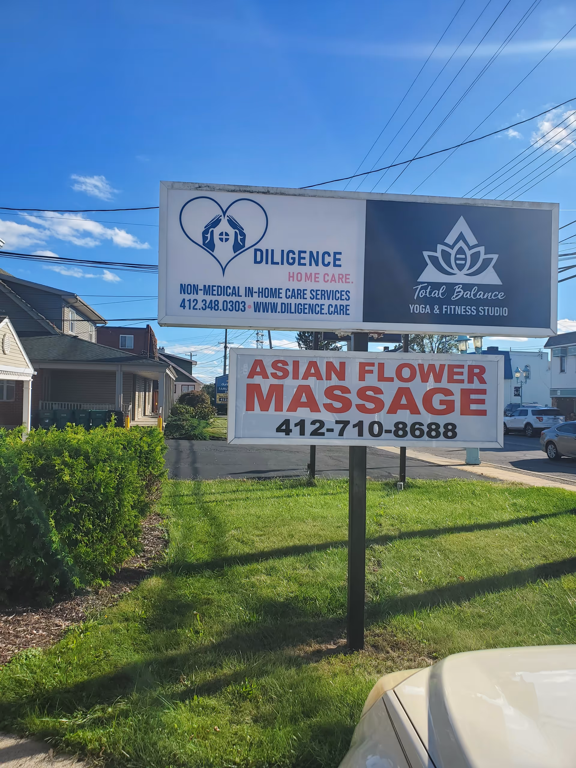 Outdoor roadside sign for Diligence Home Care with surrounding signs and greenery.