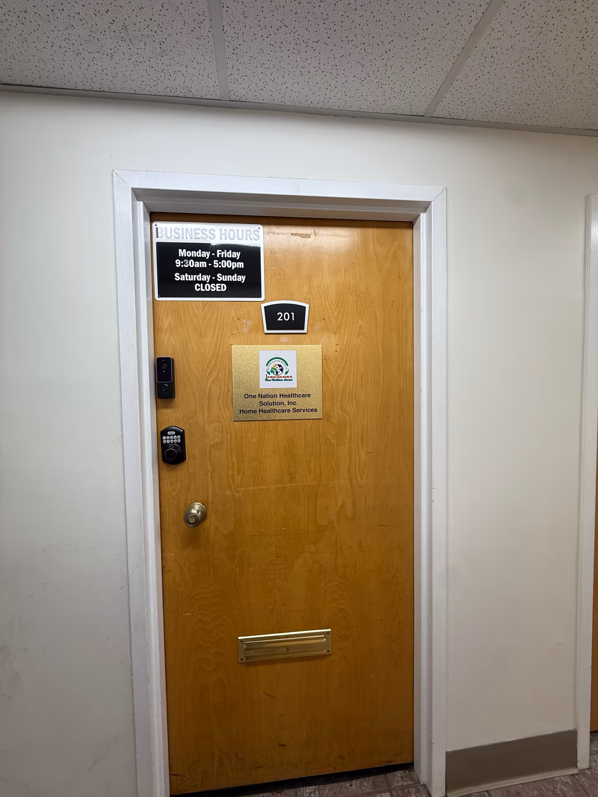Wooden interior hallway door marked 201 with a business hours sign.