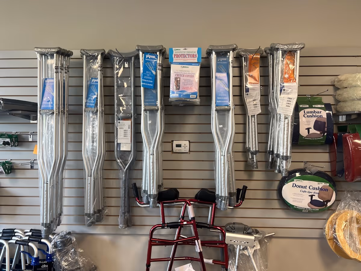 Rows of crutches and mobility aids hang on a slat-wall display in a medical rental shop.