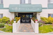 Exterior view of Pacifica Nursing and Rehab Center, green awning above glass entrance.