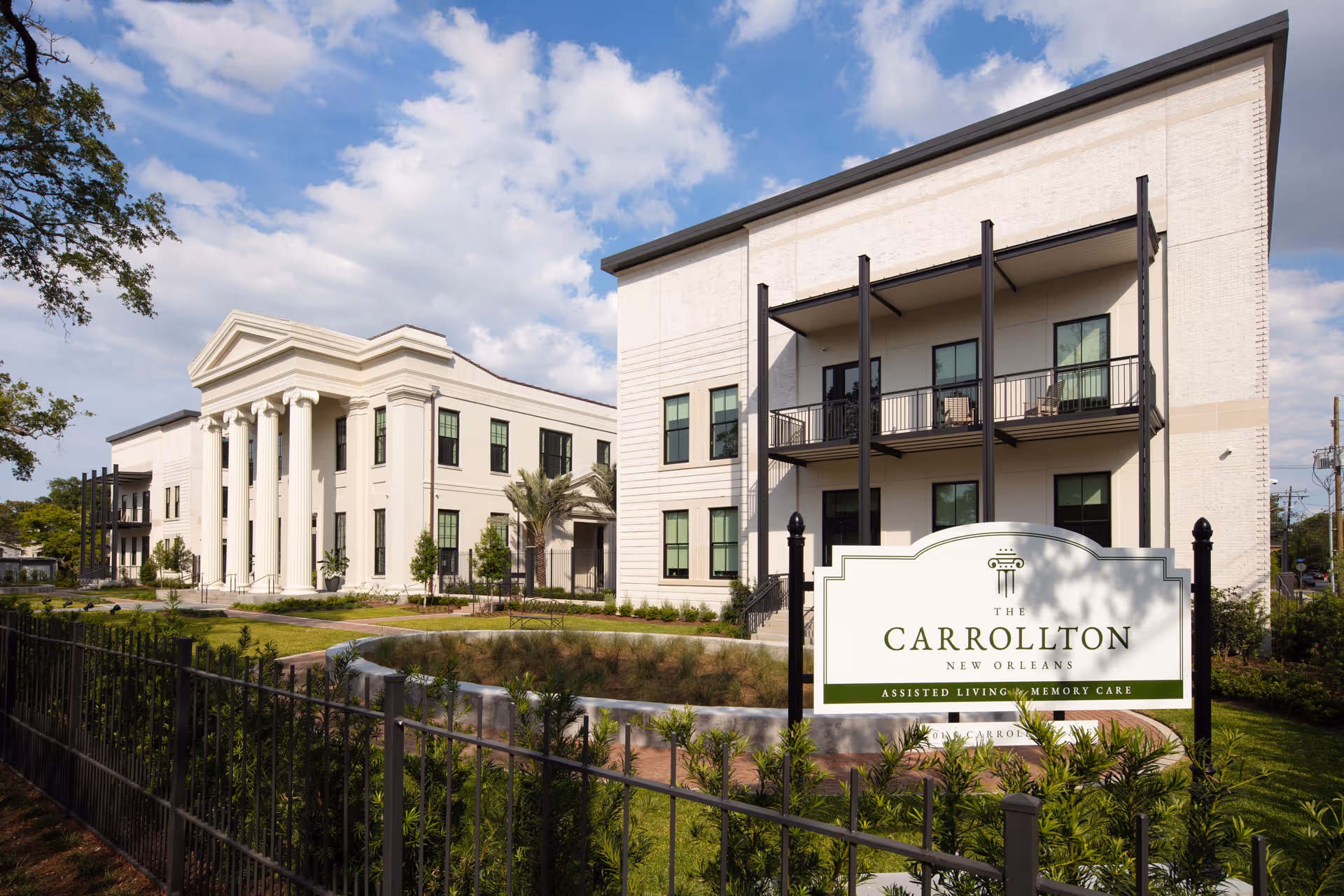 Front exterior of The Carrollton senior living facility with a sign and landscaped grounds.