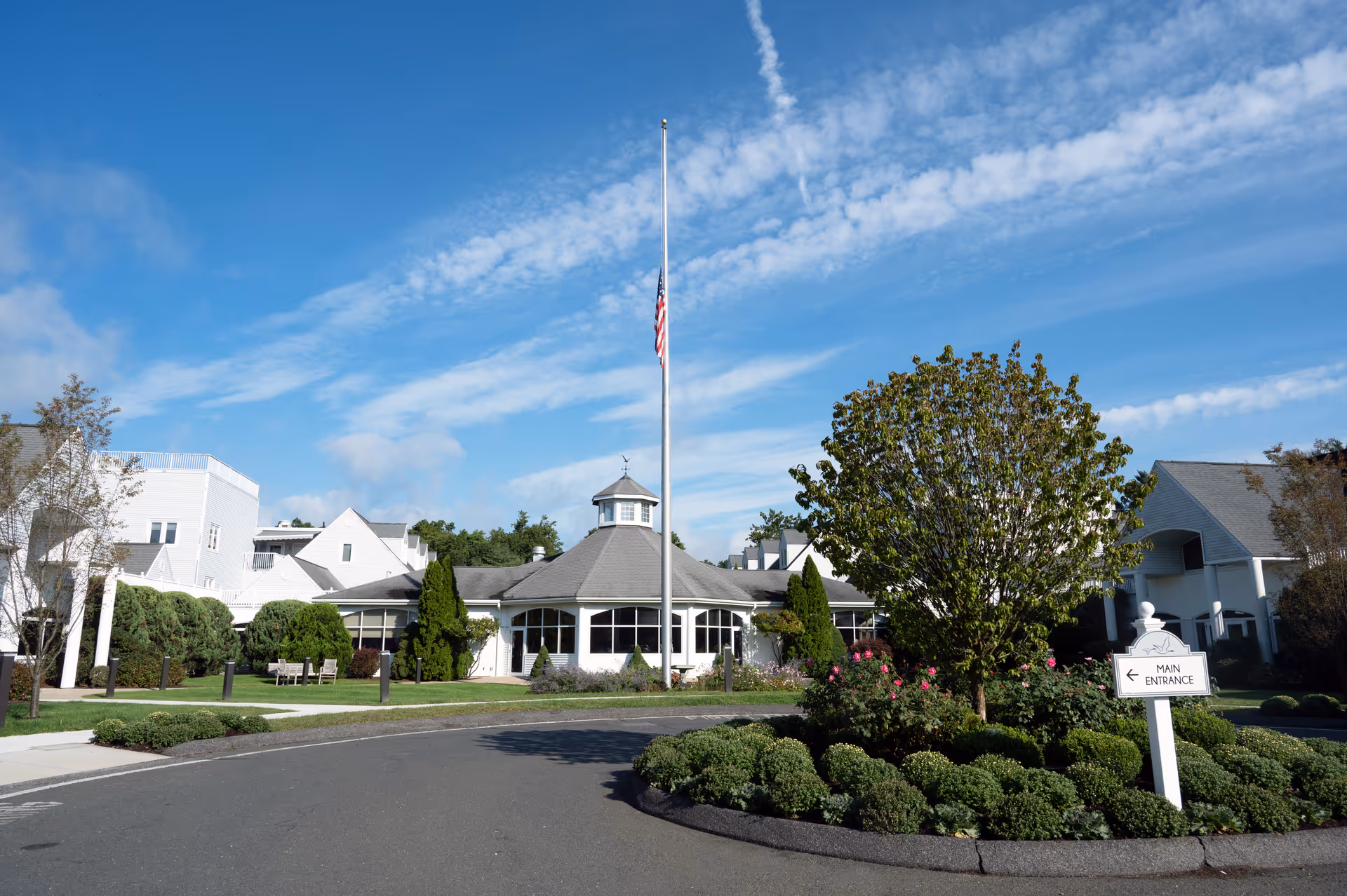 Pomperaug Woods senior living facility exterior with flagpole and main entrance sign