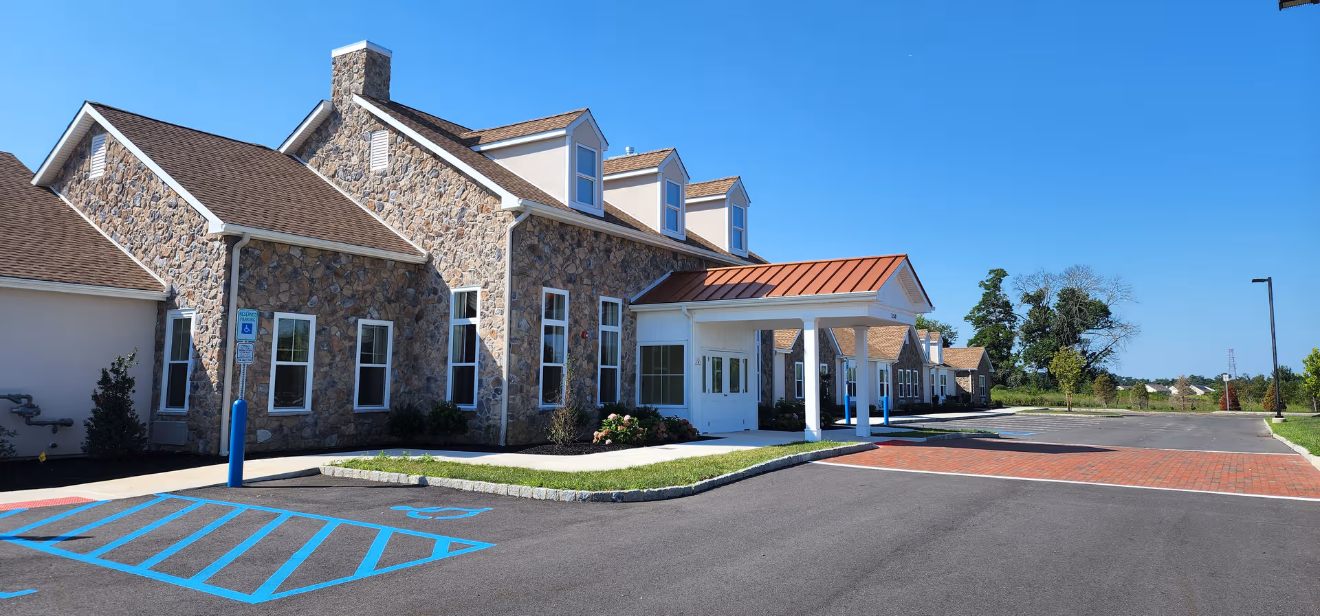 Stone-clad senior living facility exterior with a covered entrance and accessible parking.