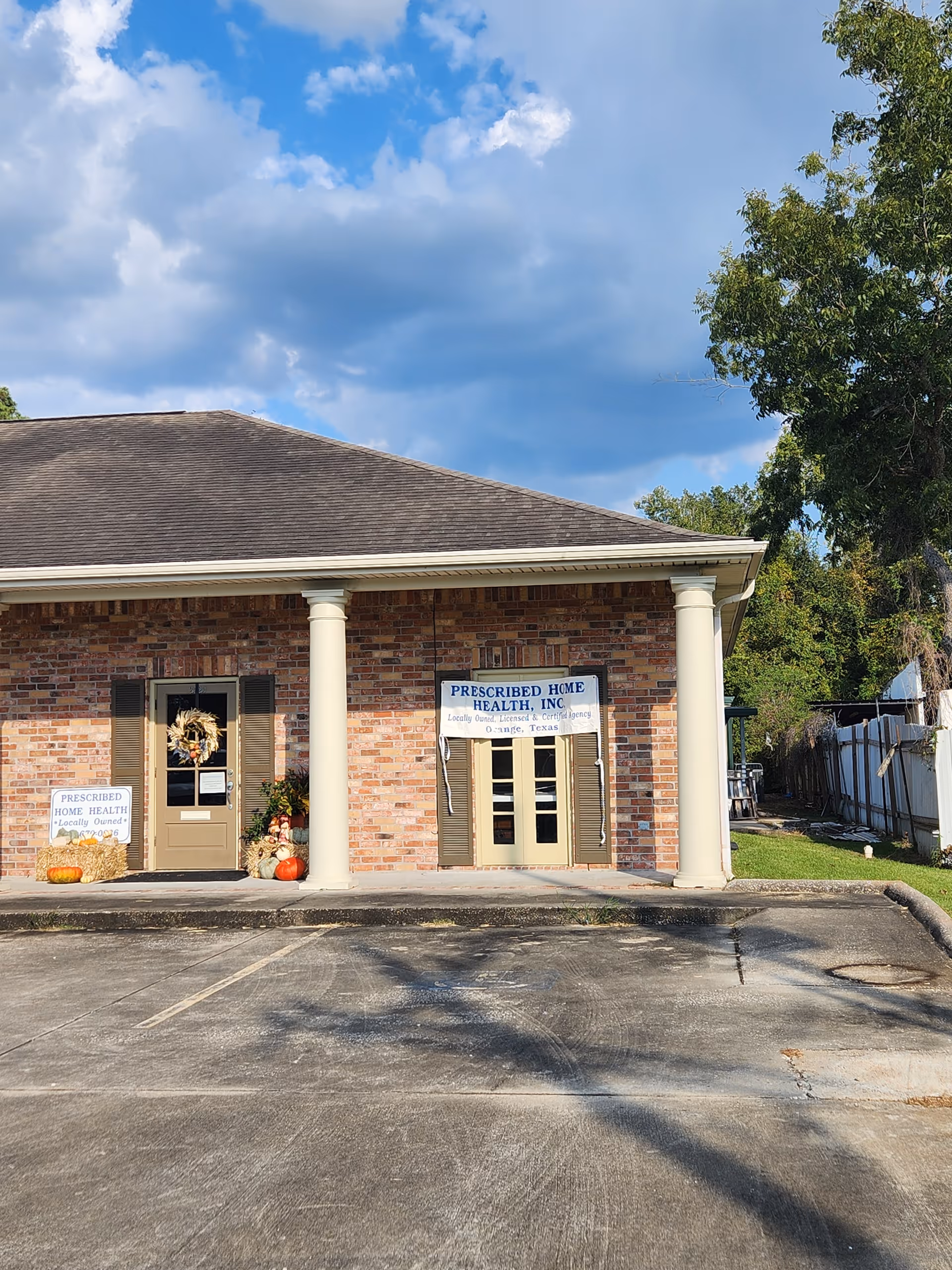 Brick storefront of Prescribed Home Health Inc with pillars, signage, and autumn pumpkins.