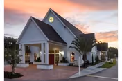Exterior view of Sunnyside Village senior living facility with covered entrance and sunset sky