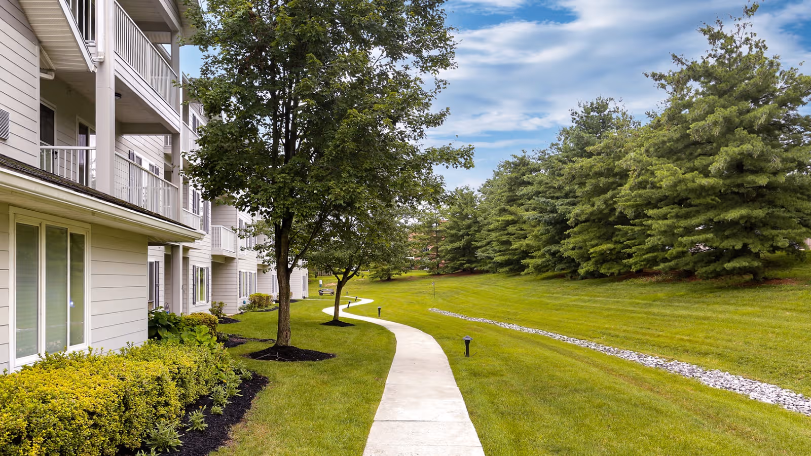 Exterior view of Holiday Manor at Oakridge with a curved path, lawn, and trees.