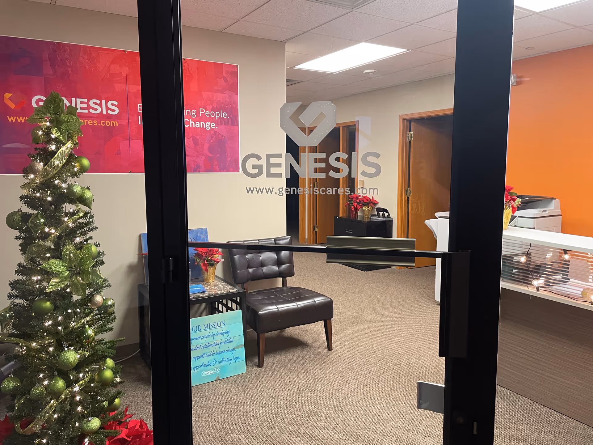 Interior reception area with glass doors, a Christmas tree, and a seating arrangement.