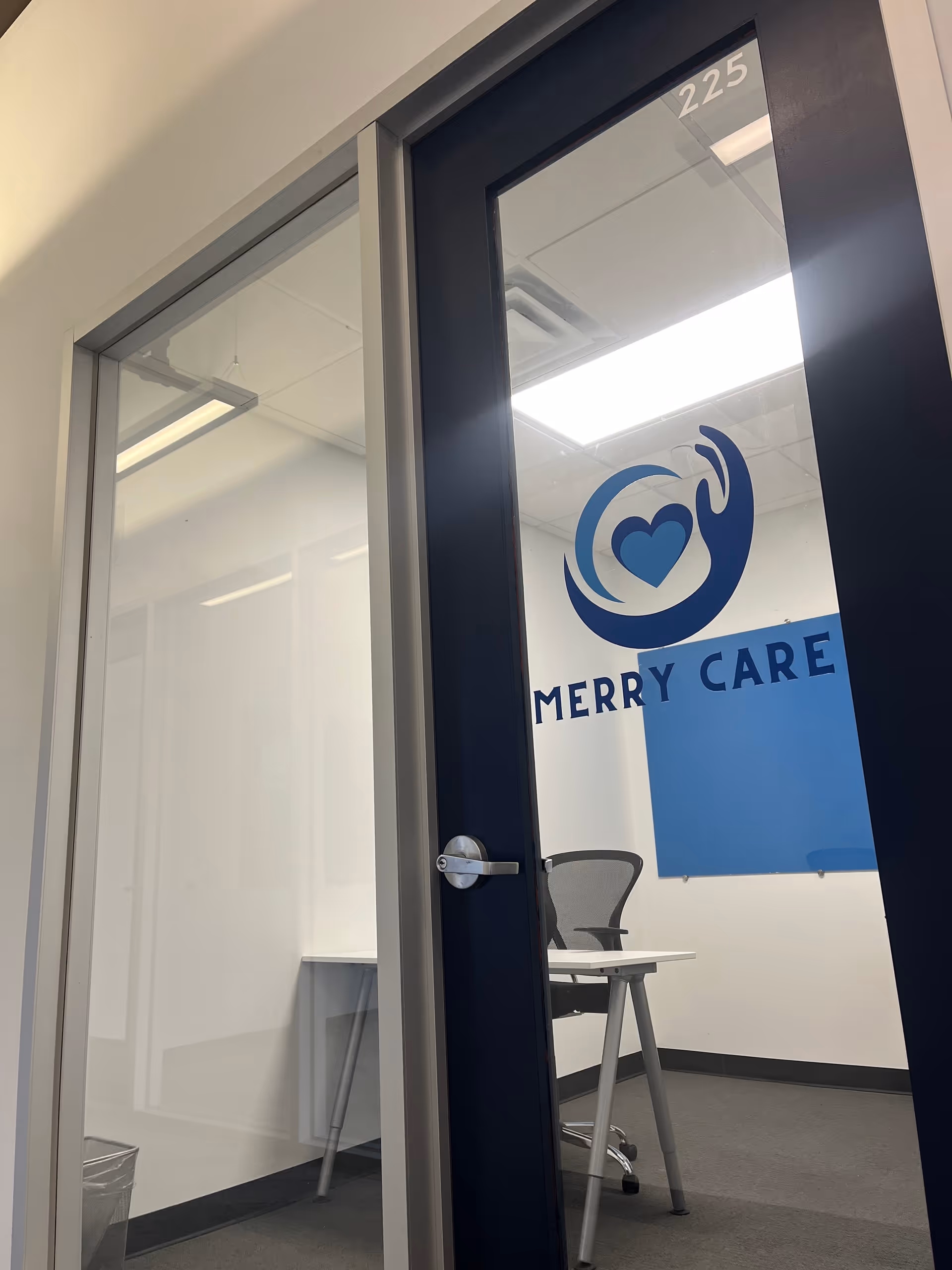 Interior door with Merry Care logo and room number 225, revealing a small office.