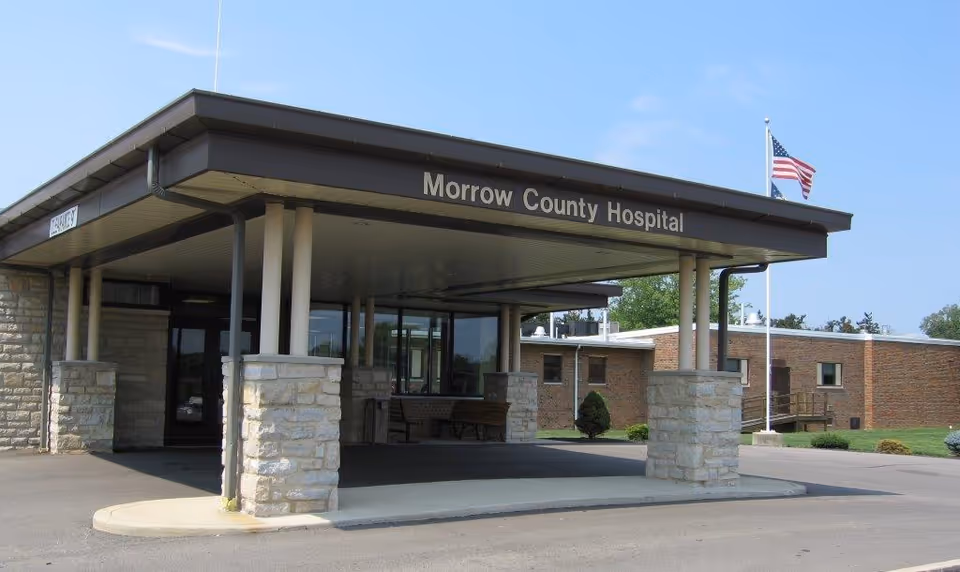 front view of Morrow County Hospital entrance with canopy, stone pillars, and American flag.