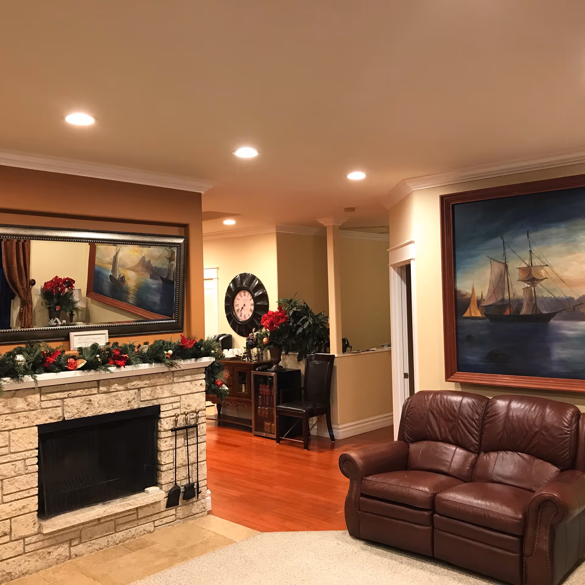 A warm living room area with a stone fireplace, leather couch, and artwork.