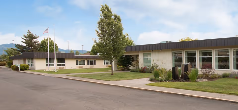 Exterior view of Avamere at Three Fountains with landscaped lawn and flagpole.