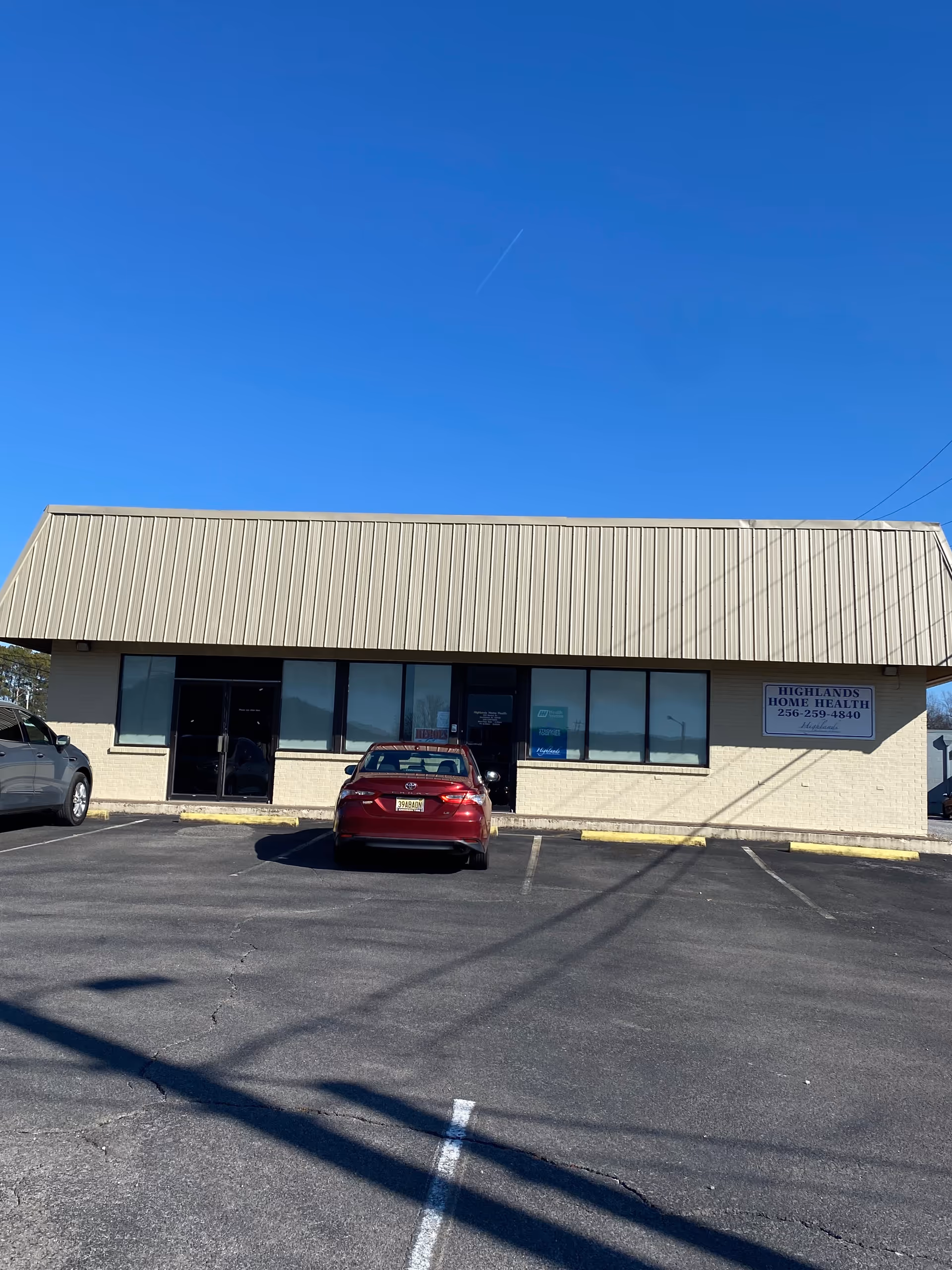 Front view of Highlands Home Health facility with parking lot and clear blue sky.