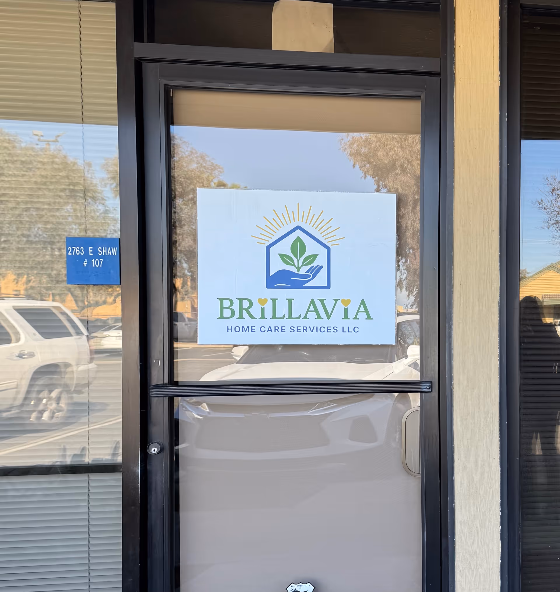 Glass door with Brillavia Home Care Services logo and exterior reflections.