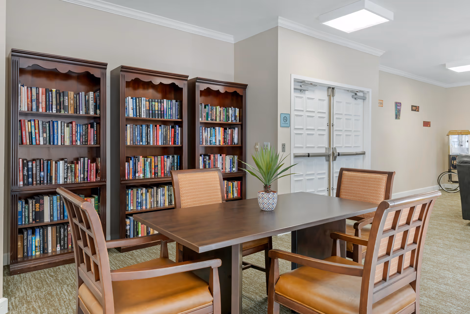Interior reading lounge at Brookdale Melbourne featuring bookshelves, a central table, and wooden chairs.