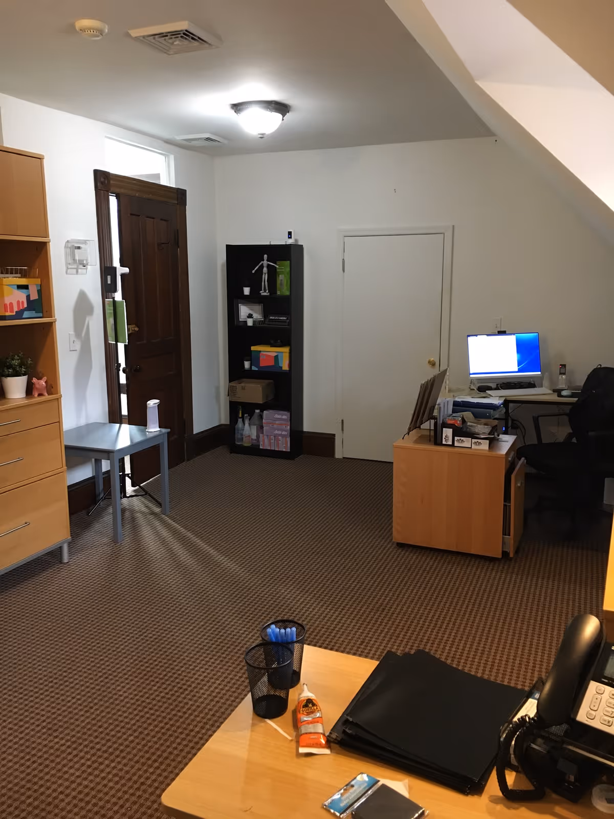Interior office area with desk, computer, shelves, and staircase in a senior facility.