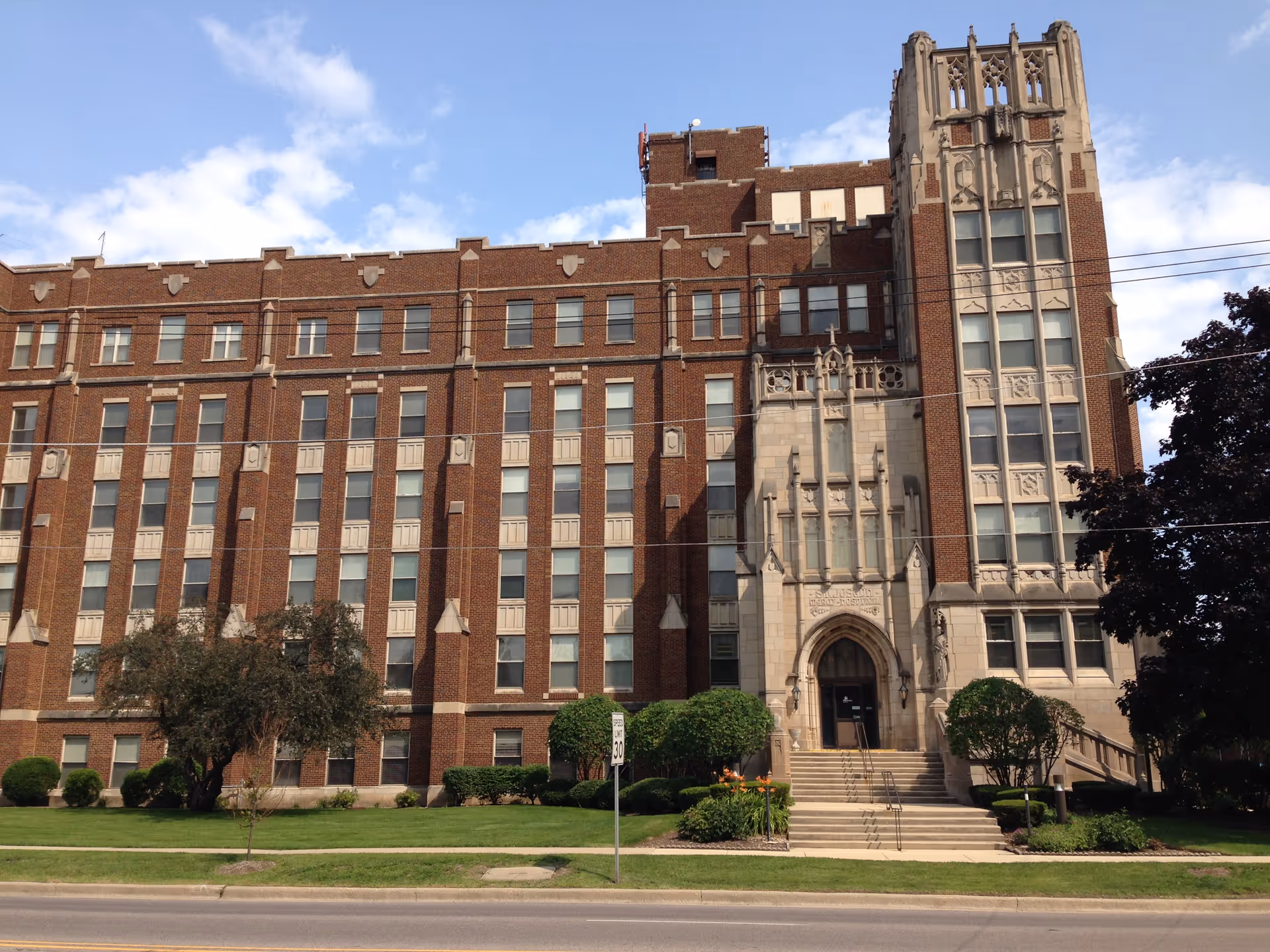 A large brick senior living facility building with Gothic detailing and a grand front entrance.